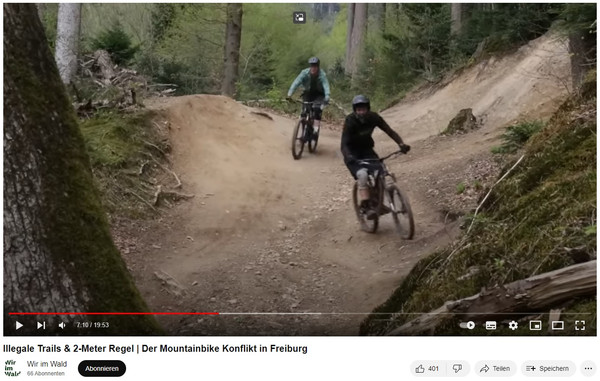 Bild aus einem Video, das zwei Mountainbiker im Wald zeigt